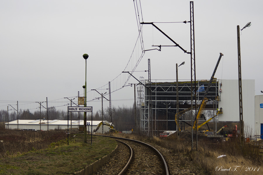 Rok 2011. Nieczynny peron przystanku Siedlce Wschodnie przy torze linii do Siemianówki. W tle rozbudowa zakładu Stadlera.